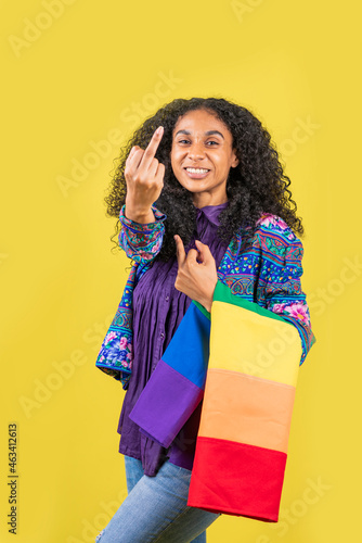 Mujer afroamericana haciendo un gesto con su dedo y con la bandera de la diversidad en su brazo
