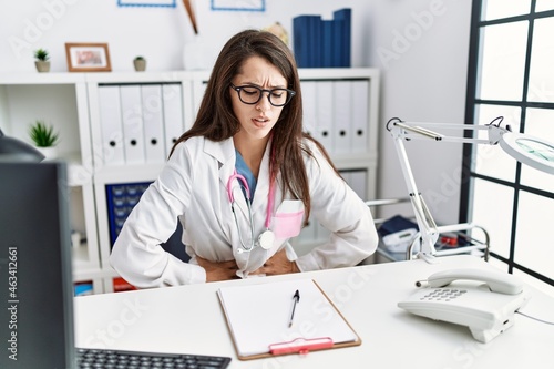 Young doctor woman wearing doctor uniform and stethoscope at the clinic with hand on stomach because nausea, painful disease feeling unwell. ache concept.