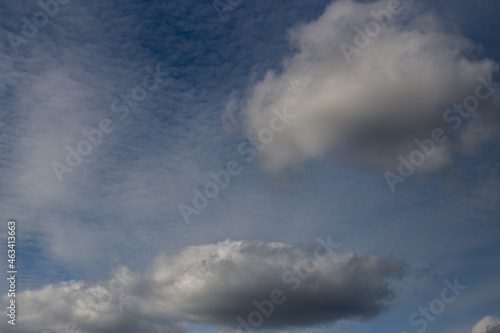 Light white clouds fly across a bright blue sky. Clear sky at sunny summer afternoon. Spring cloudscape background. Copy space