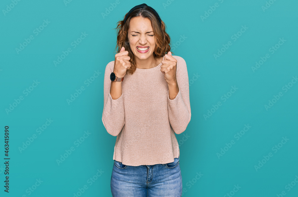 Fototapeta premium Beautiful young caucasian woman wearing casual sweater excited for success with arms raised and eyes closed celebrating victory smiling. winner concept.