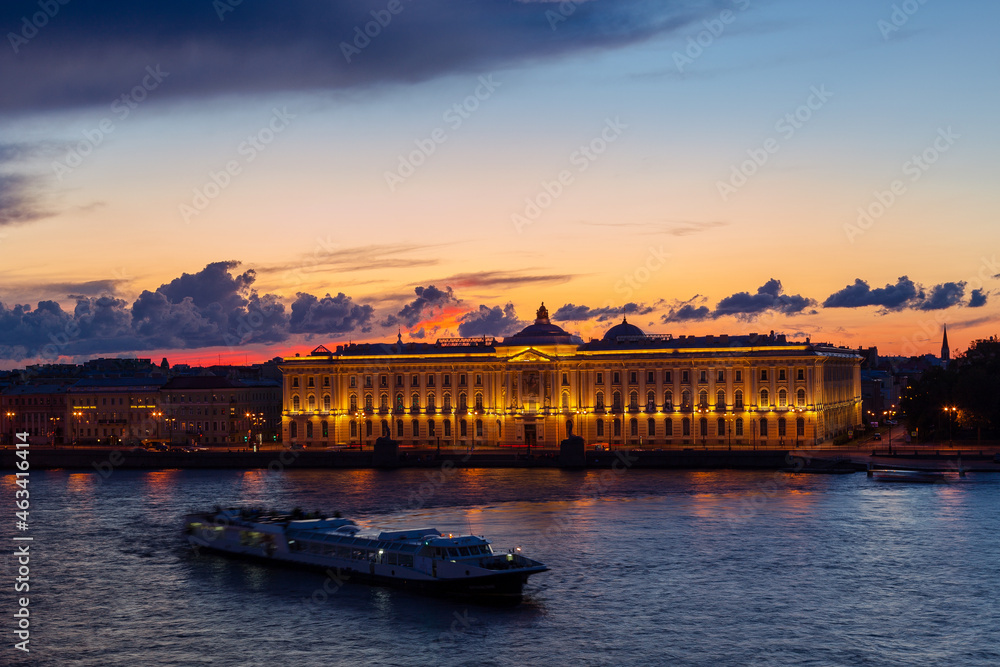 Illuminated Russian Academy of Arts in Saint Petersburg, Russia. Blurred drifting boat in the middle of river. Beautiful sunset landscape. Travel destination. Place for vacation. Wanderlust concept.