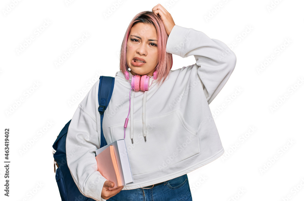 Hispanic woman with pink hair wearing student backpack and headphones confuse and wondering about question. uncertain with doubt, thinking with hand on head. pensive concept. Hispanic woman with pink hair wearing student backpack and headphones confuse and wondering about question. uncertain with doubt, thinking with hand on head. pensive concept.