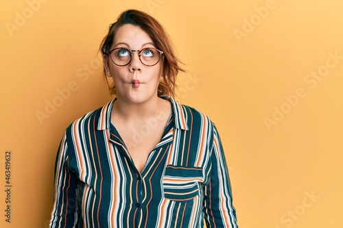 Young caucasian woman wearing casual clothes and glasses making fish face with lips, crazy and comical gesture. funny expression.