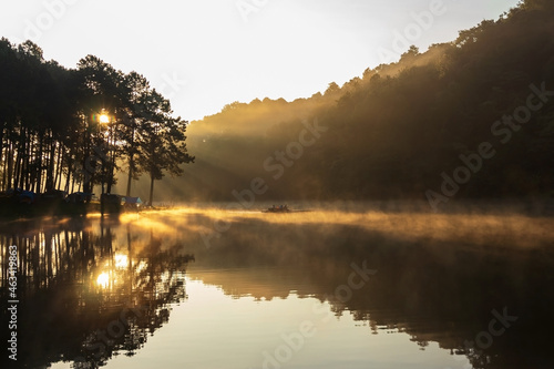 The beautiful morning with beams of sunlight pierce through the forest with morning fog over water at PangUng Lake in Mae Hong Son  north of Thailand.