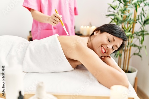 Middle age hispanic woman smiling confident having aloe vera cream back massage at beauty center