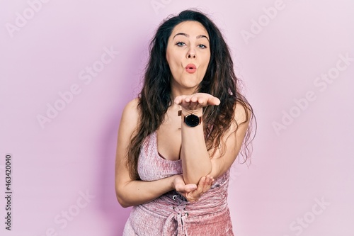 Young hispanic woman wearing casual clothes looking at the camera blowing a kiss with hand on air being lovely and sexy. love expression.