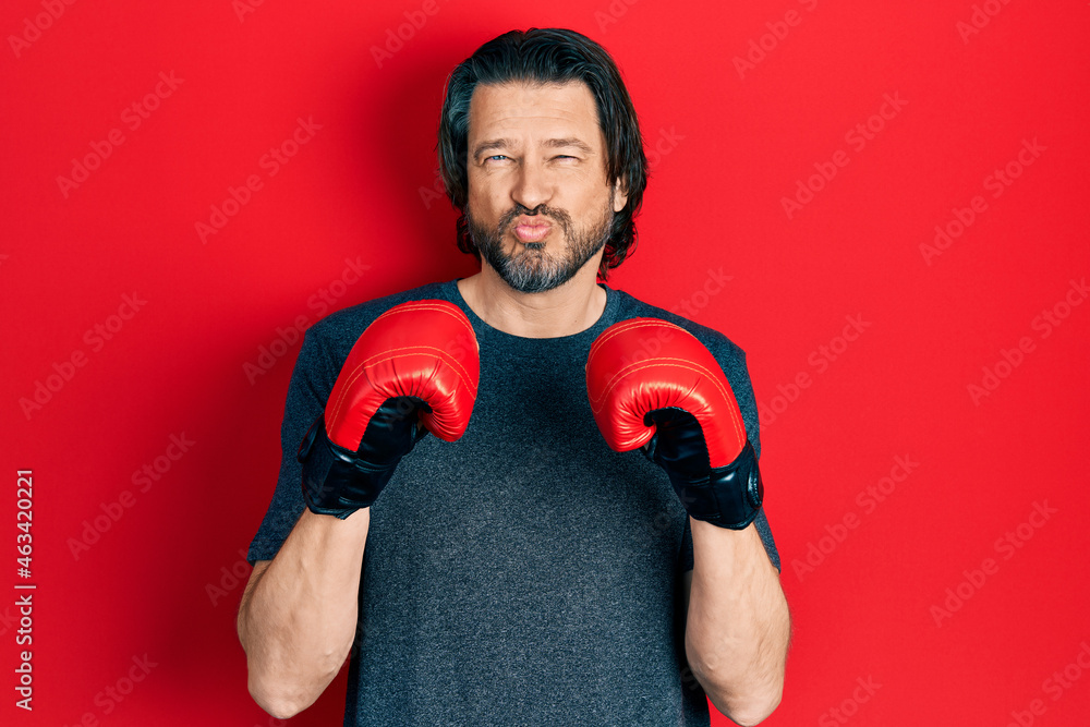 Middle age caucasian man using boxing gloves looking at the camera blowing a kiss being lovely and sexy. love expression.