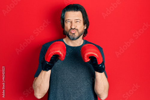 Middle age caucasian man using boxing gloves looking at the camera blowing a kiss being lovely and sexy. love expression.