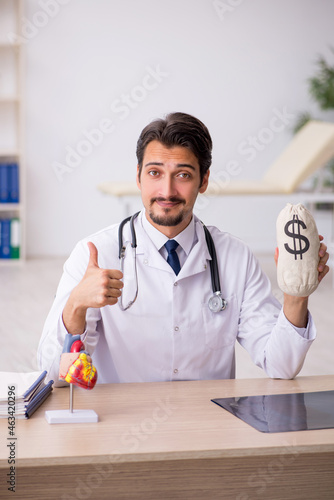 Young male doctor cardiologist holding monebag