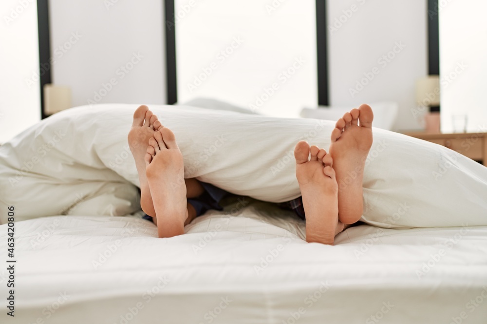 Couple feet under sheets on the bed at home. Couple feet under sheets on the bed at home.