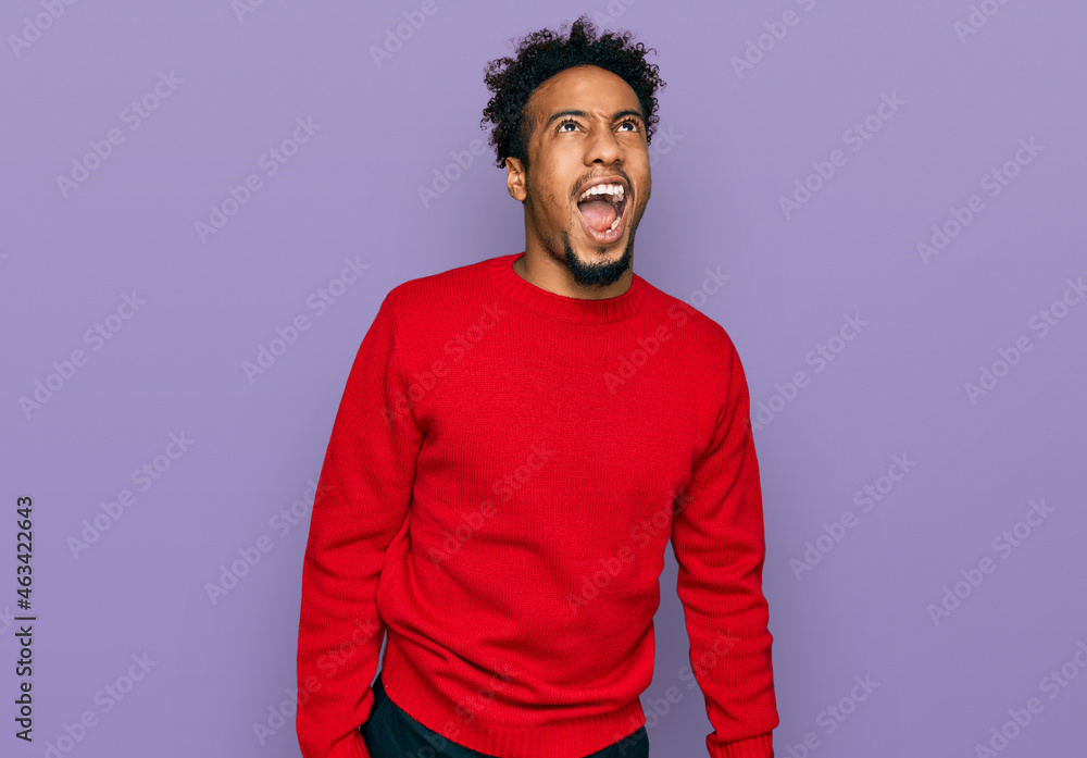 Young african american man with beard wearing casual winter sweater angry and mad screaming frustrated and furious, shouting with anger. rage and aggressive concept. Young african american man with beard wearing casual winter sweater angry and mad screaming frustrated and furious, shouting with anger. rage and aggressive concept.