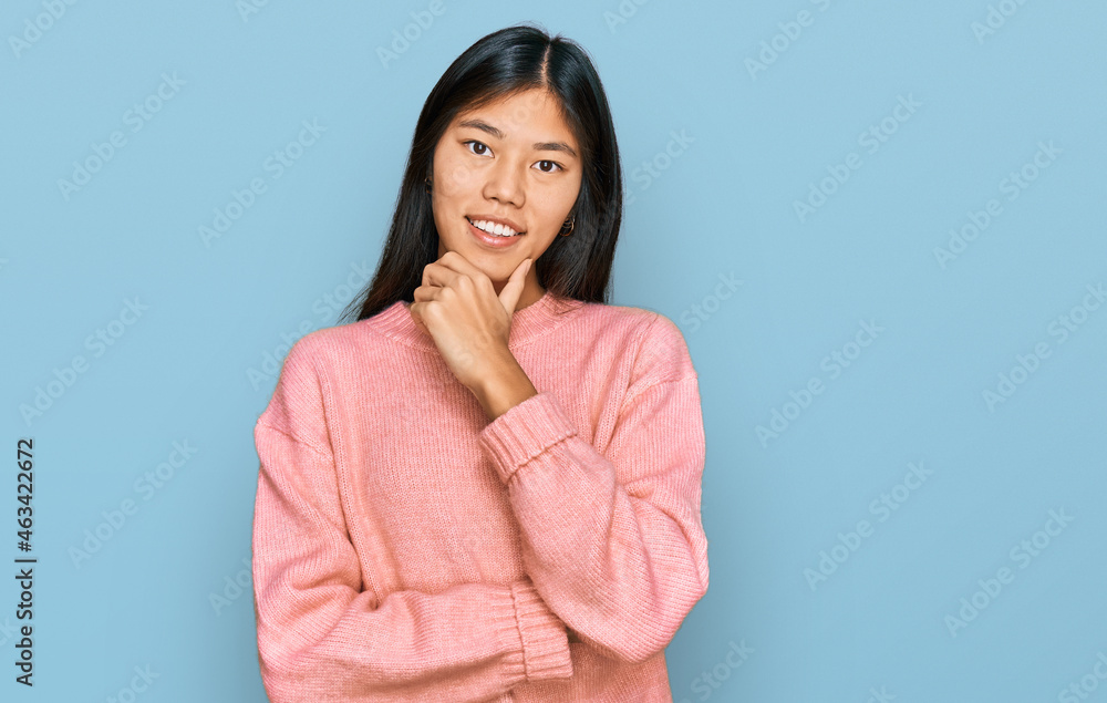 Beautiful young asian woman wearing casual winter sweater looking confident at the camera smiling with crossed arms and hand raised on chin. thinking positive. Beautiful young asian woman wearing casual winter sweater looking confident at the camera smiling with crossed arms and hand raised on chin. thinking positive.
