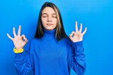 Young brunette girl wearing turtleneck sweater relaxed and smiling with eyes closed doing meditation gesture with fingers. yoga concept.