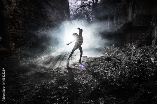 A young witch dances and conjures on Halloween night in smoke and light at the festival of the dead.