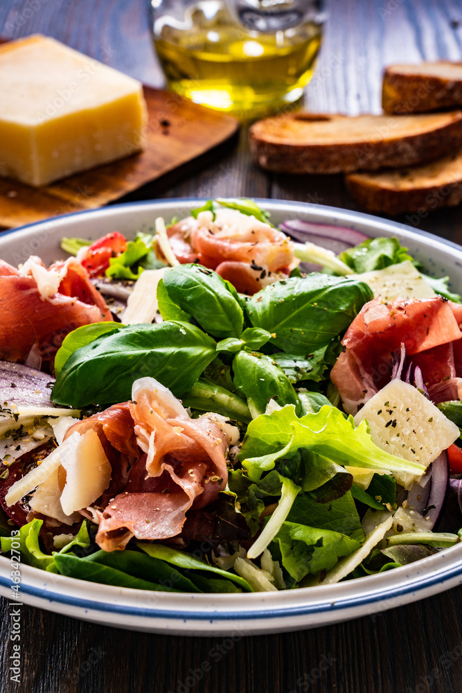 Tasty salad - prosciutto di Parma, parmesan and fresh, green vegetables on wooden table
 - obrazy, fototapety, plakaty 