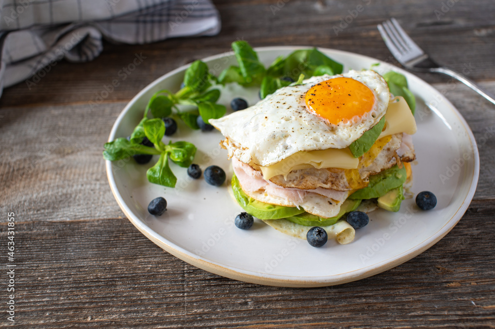 Keto breakfast sandwich with fried eggs, ham, cheese, and avocado. Served with fresh blueberries and lamb´s lettuce Keto breakfast sandwich with fried eggs, ham, cheese, and avocado. Served with fresh blueberries and lamb´s lettuce