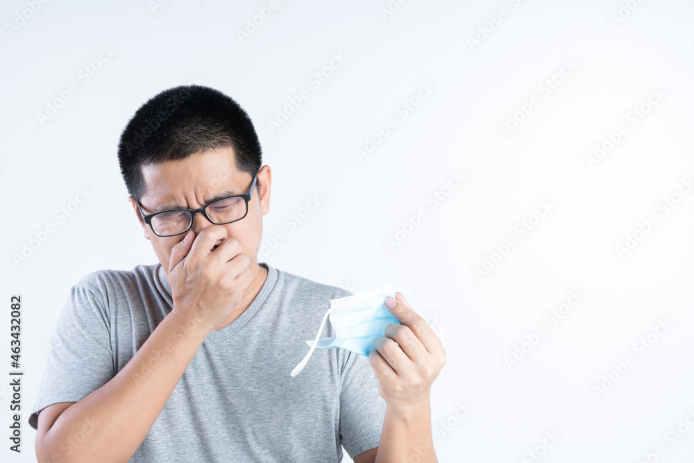 Middle aged Asian man blocking his nose from bad smell or the pain from wearing mask Middle aged Asian man blocking his nose from bad smell or the pain from wearing mask