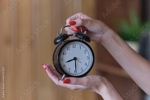 black alarm clock in woman hands, concept of menopause, or wasting time