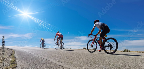 Fototapeta Cycling race on an uphill road in Ioannina, Greece, four bikers and bikes  sun