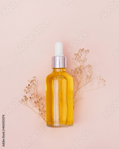 glass bottle with serum on a light background with sun glare