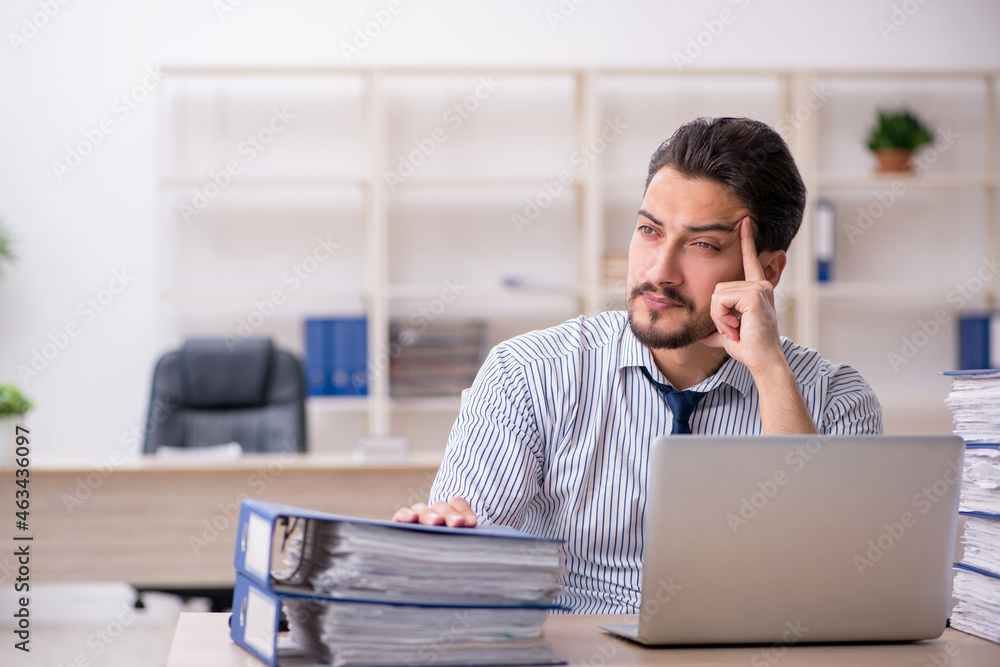 Young male employee and too much work in the office Young male employee and too much work in the office