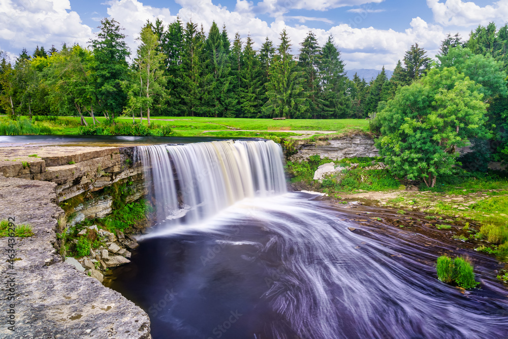 Large river waterfall falling down the cliff in a green forest landscape of northern Europe. Large river waterfall falling down the cliff in a green forest landscape of northern Europe.