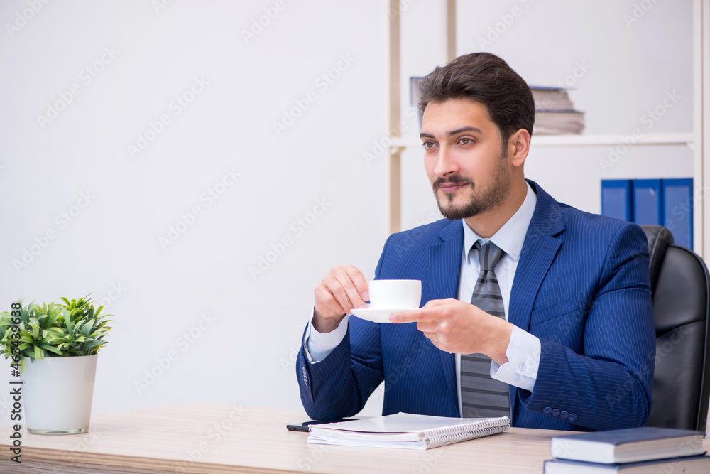 Young handsome employee drinking coffee during break Young handsome employee drinking coffee during break