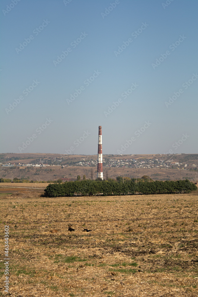 Thermal power plant pipe towering over power lines