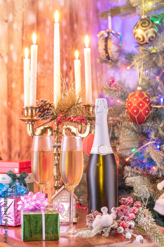 Glasses of champagne and gifts composition with lit up candelabra .