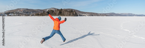 Winter fun happy people jumping of joy on frozen white snow, nature landscape banner, Canada. Warm outerwear and accessories for outdoor activity photo