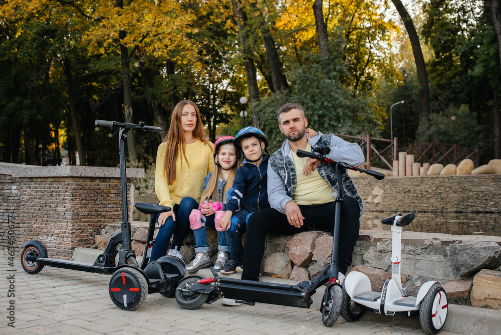 A large happy family rides Segways and electric scooters in the Park on a warm autumn day during sunset. Family vacation in the Park. A large happy family rides Segways and electric scooters in the Park on a warm autumn day during sunset. Family vacation in the Park.