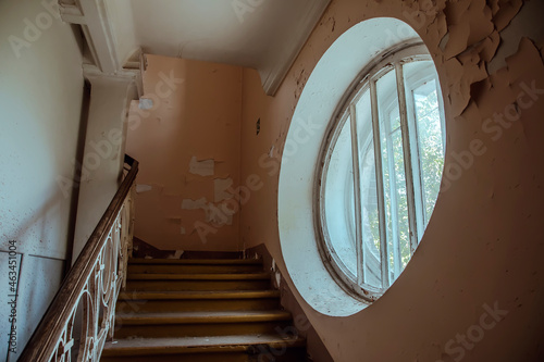 A beautiful round window in an old abandoned hospital. Ancient staircase. The interior of an abandoned building. Beautiful ancient architecture.
