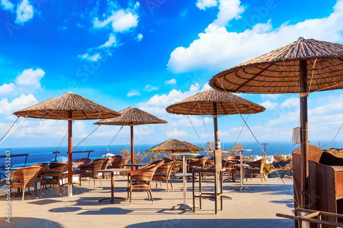 Restaurant with straw umbrellas in Oia village on Santorini island, Aegean sea, Greece.