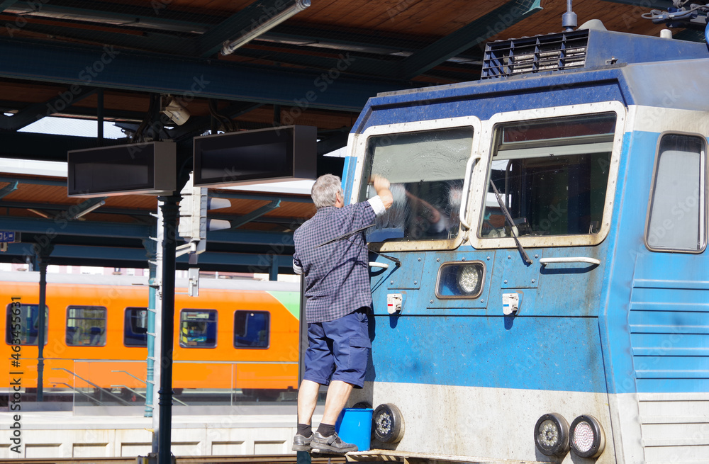 Train driver cleans the windows of the locomotive