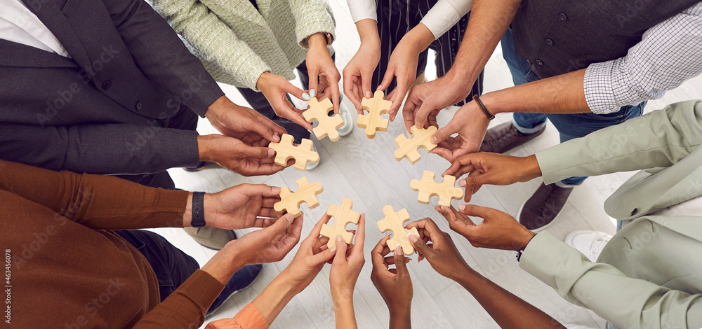 Banner background with multiethnic group of young people standing together  and joining pieces of jigsaw puzzle as metaphor for business team and  teamwork. Cropped shot of hands holding jigsaw parts Stock Photo |