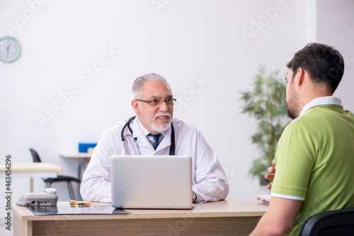 Young man visiting old male doctor