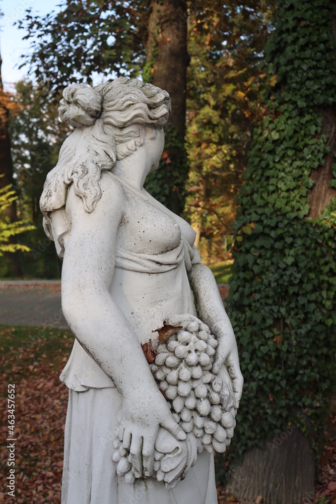 statue of a girl with flowers and grapes in a basket half-naked greek sculpture