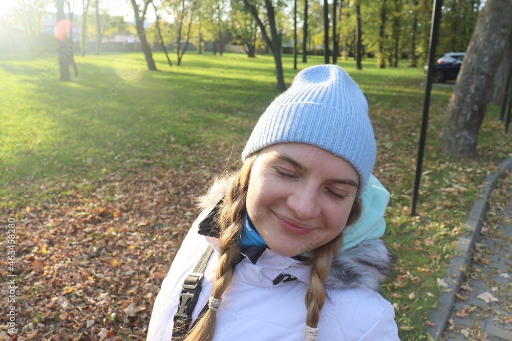 a young girl rejoices in the sun that breaks through the crowns of trees in an old park in an autumn warm afternoon a young girl rejoices in the sun that breaks through the crowns of trees in an old park in an autumn warm afternoon