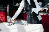 A young waiter in a stylish uniform is engaged in serving the table in a beautiful gourmet restaurant close-up. Restaurant activity, of the highest level.