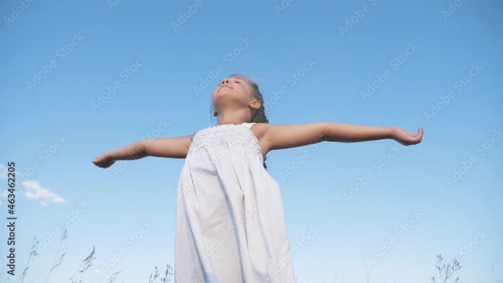 Happy child on background sky.girl stands with raised arms in sunny blue sky outdoors.child enjoys freedom, happiness, raising his hands up.girl of freedom, happiness, enjoying nature while traveling. Happy child on background sky.girl stands with raised arms in sunny blue sky outdoors.child enjoys freedom, happiness, raising his hands up.girl of freedom, happiness, enjoying nature while traveling.