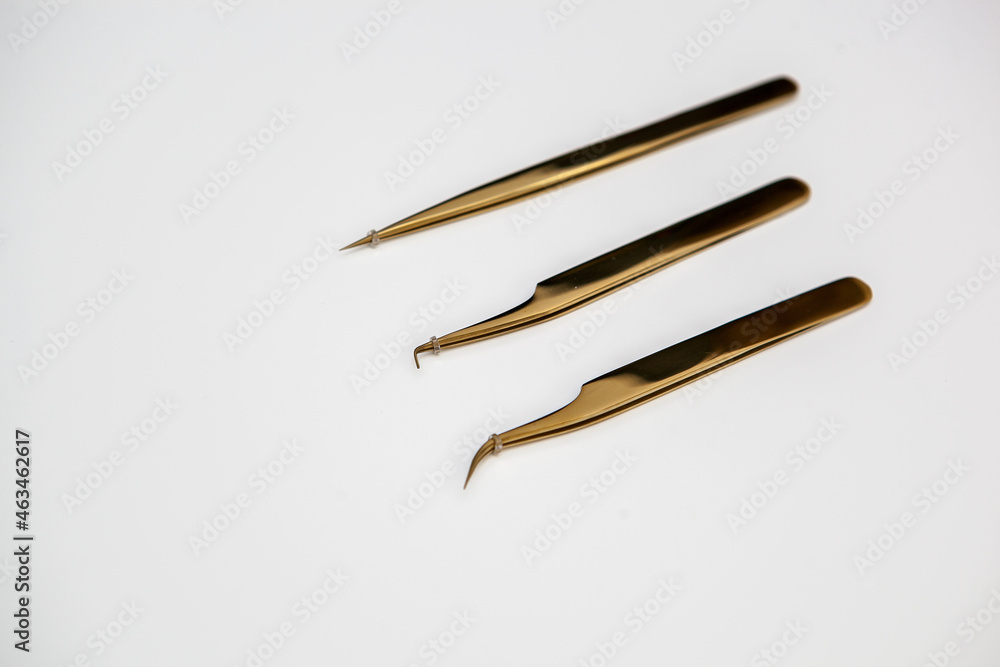 tools for eyelash extensions and eyebrow design. cosmetic tweezers in gold color on a white background tools for eyelash extensions and eyebrow design. cosmetic tweezers in gold color on a white background