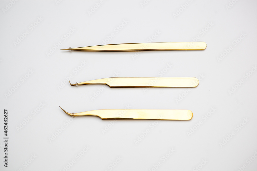 tools for eyelash extensions and eyebrow design. cosmetic tweezers in gold color on a white background tools for eyelash extensions and eyebrow design. cosmetic tweezers in gold color on a white background