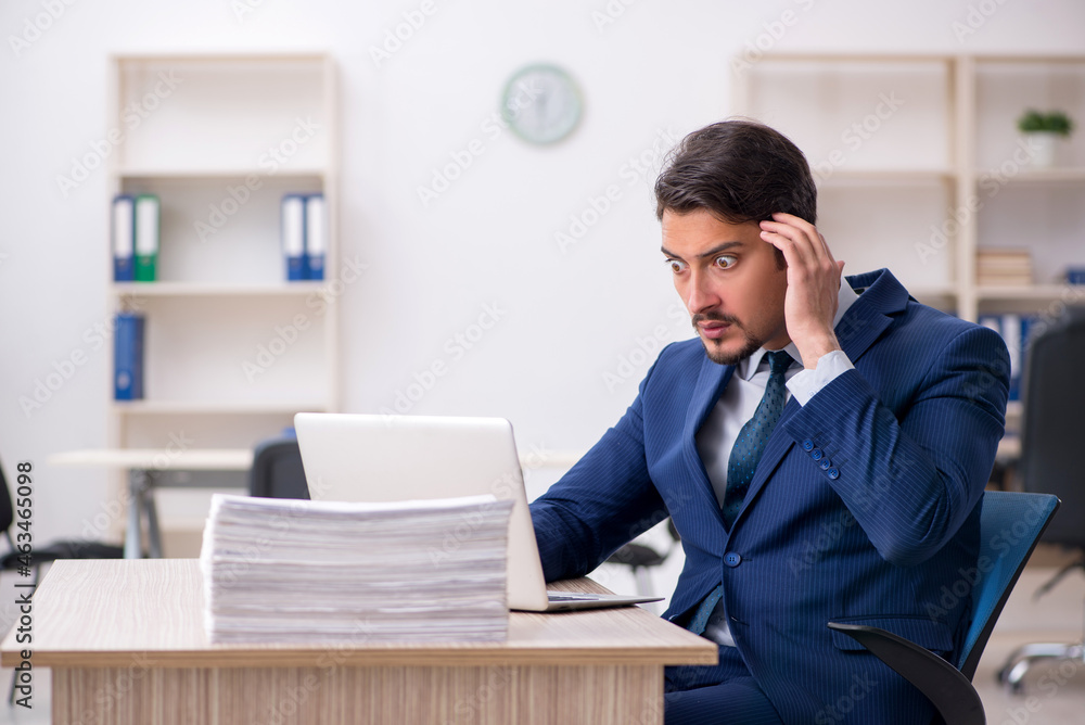 Young male employee and too much work in the office Young male employee and too much work in the office