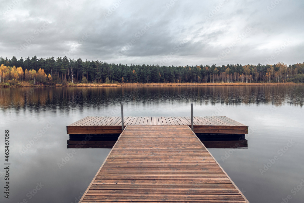 Wooden pier on the forest lake on rainy autumn day