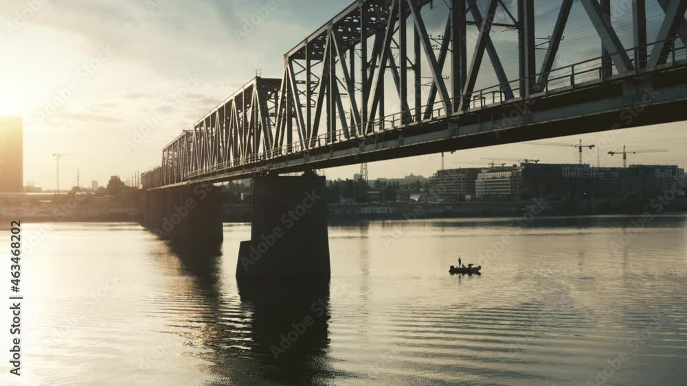Sunrise sun over railway bridge and city river. Logistics and transportation. Intercity railway connection, city electric metro train. Railroad modern crossover. Aerial flight over bridge silhouette Sunrise sun over railway bridge and city river. Logistics and transportation. Intercity railway connection, city electric metro train. Railroad modern crossover. Aerial flight over bridge silhouette