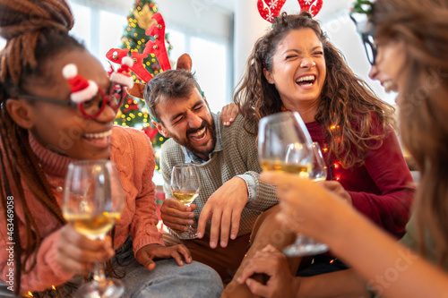 Friends laughing and drinking wine while celebrating Christmas at home