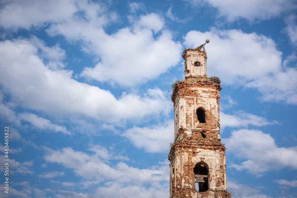 A beautiful red brick tower of a ruined church against a blue sky with clouds.