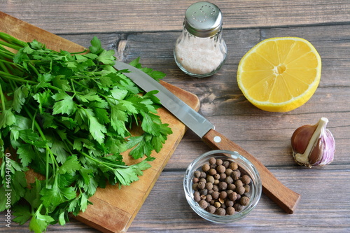 green parsley on cutting board with lemon and spices on wooden background  food design