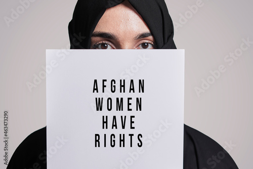 Muslim woman holding a paper with text - Afghan women have rights. Muslim woman in traditional hijab clothing. Domestic violence, discrimination of Muslim women
