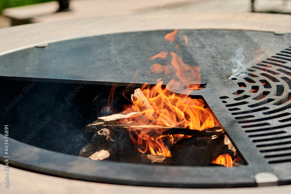 Kettle Grill Pit with Cast Iron Grid with flames . Round table-cooking surface. Hot BBQ on Backyard Kettle Grill Pit with Cast Iron Grid with flames . Round table-cooking surface. Hot BBQ on Backyard